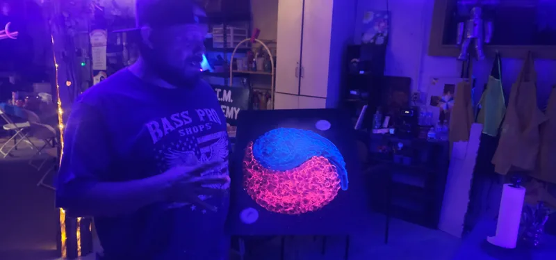 A canvas painted in ultraviolet-reactive colour, glowing under blacklight